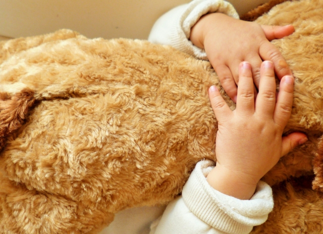 子どもがぬいぐるみを抱きかかえている